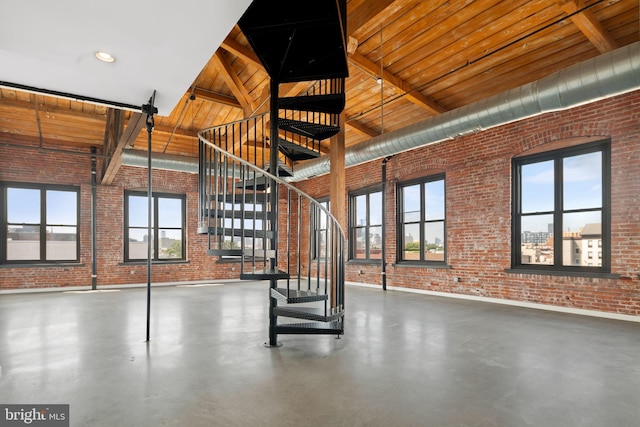 1147 N 4th St Unit 6F, Philadelphia, PA 19123 - unfurnished living room featuring brick wall, high vaulted ceiling, finished concrete flooring, stairway, and wood ceiling with exposed beams