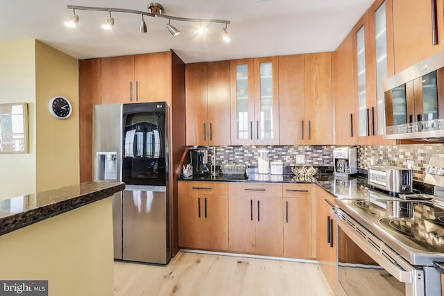 910 M St NW Unit 1022, Washington, DC 20001 - kitchen with stainless steel appliances, backsplash, light wood-style flooring, and dark stone countertops