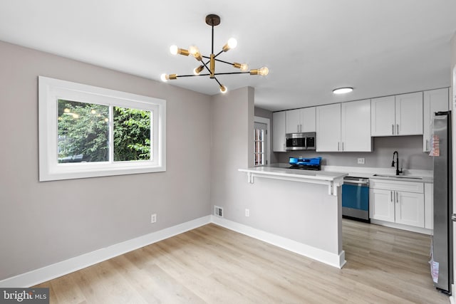 2723 Keating St, Temple Hills, MD 20748 - kitchen featuring appliances with stainless steel finishes, a sink, a chandelier, light countertops, and white cabinetry