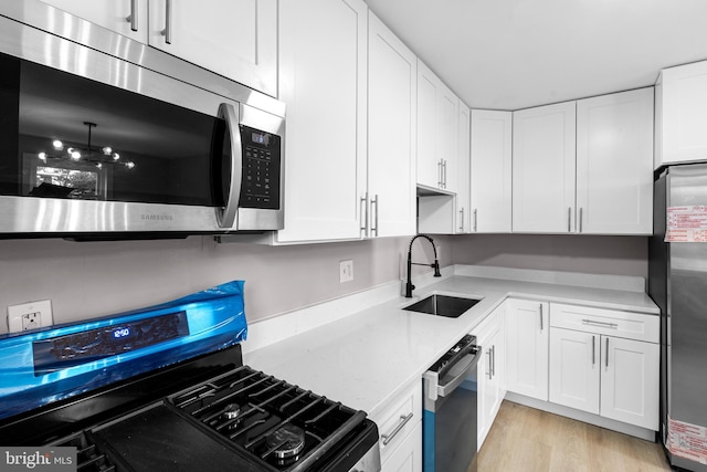 2723 Keating St, Temple Hills, MD 20748 - kitchen featuring stainless steel appliances, a sink, white cabinetry, light wood-type flooring, and light stone countertops