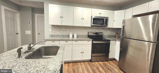 320 Third St, Fredericksburg, VA 22408 - kitchen featuring stainless steel appliances, light wood finished floors, white cabinets, and decorative backsplash