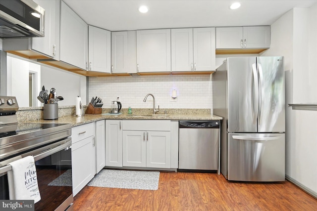 7100 Cipriano Springs Dr, Lanham, MD 20706 - kitchen featuring stainless steel appliances, a sink, light wood-style flooring, light stone countertops, and tasteful backsplash