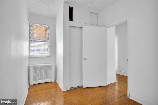 2637 S Bouvier St, Philadelphia, PA 19145 - unfurnished bedroom featuring radiator, wood finished floors, baseboards, a closet, and a textured ceiling
