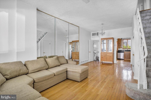 2637 S Bouvier St, Philadelphia, PA 19145 - living room featuring light wood-type flooring, a chandelier, stairs, and a textured ceiling