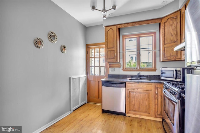 2637 S Bouvier St, Philadelphia, PA 19145 - kitchen with appliances with stainless steel finishes, a sink, dark countertops, light wood-type flooring, and brown cabinetry