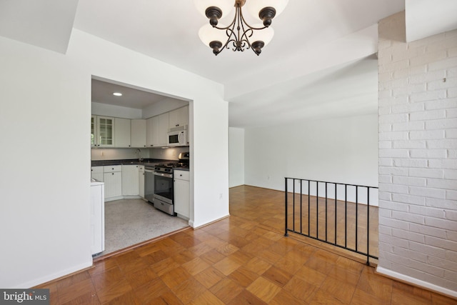2114 Bonnywood Ln Unit 201, Silver Spring, MD 20902 - kitchen with stainless steel gas range, white microwave, dark countertops, a chandelier, and white cabinetry