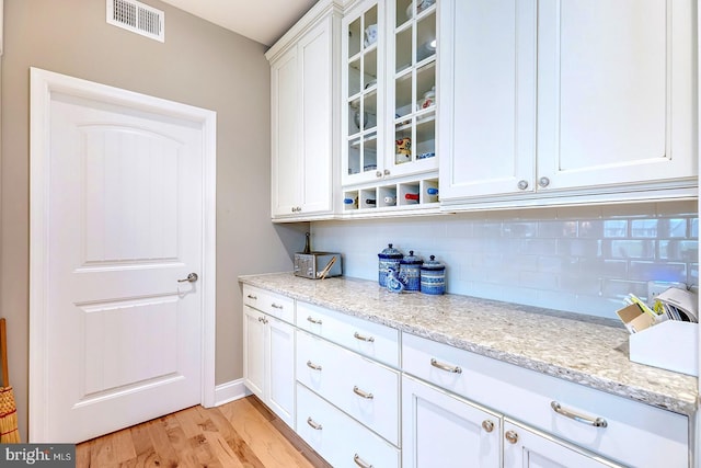 30957 Fowlers Path, Millsboro, DE 19966 - kitchen with backsplash, white cabinetry, glass insert cabinets, light wood finished floors, and light stone countertops
