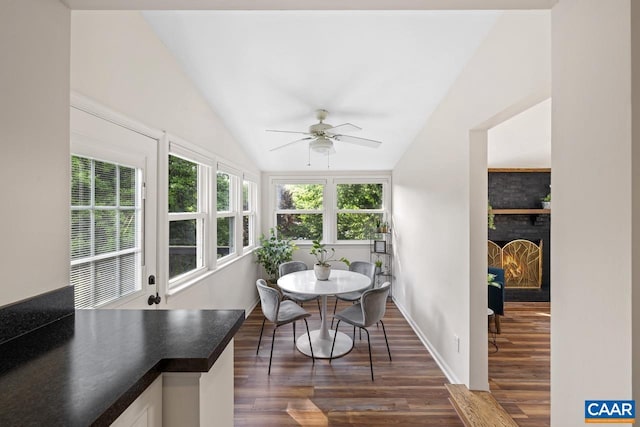1007 Saint Charles Ave, Charlottesville, VA 22901 - dining room featuring dark wood-style floors, vaulted ceiling, ceiling fan, a lit fireplace, and baseboards