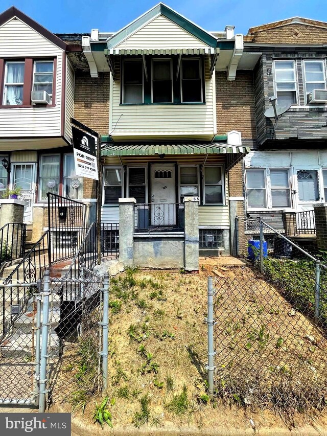 6065 Chester Ave, Philadelphia, PA 19142 - townhome / multi-family property with covered porch, a fenced front yard, brick siding, a gate, and cooling unit