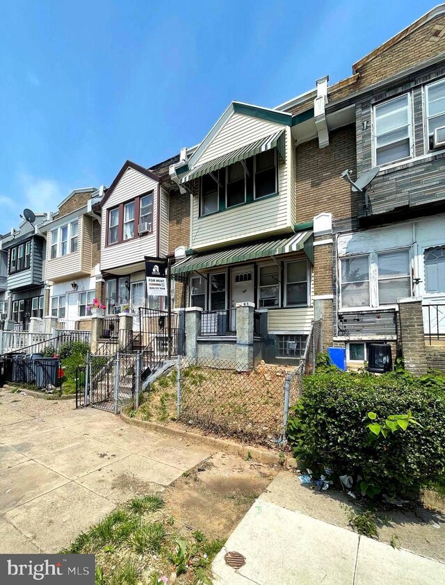 6065 Chester Ave, Philadelphia, PA 19142 - view of property with covered porch, a residential view, cooling unit, brick siding, and a gate