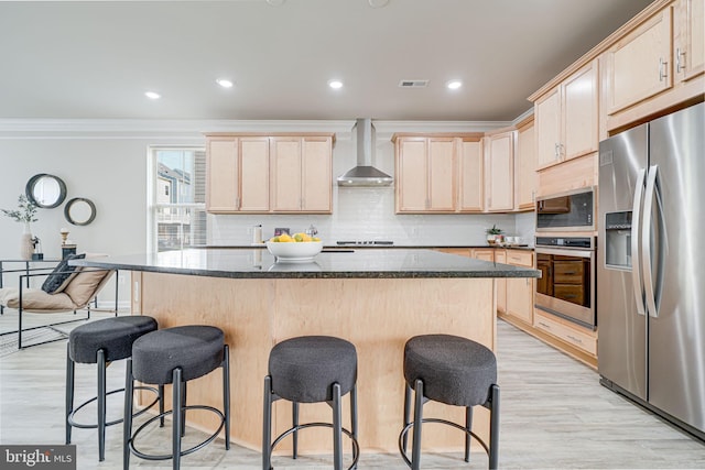 9563 Jefferson St, Manassas, VA 20110 - kitchen with stainless steel appliances, light brown cabinets, wall chimney exhaust hood, a kitchen bar, and ornamental molding
