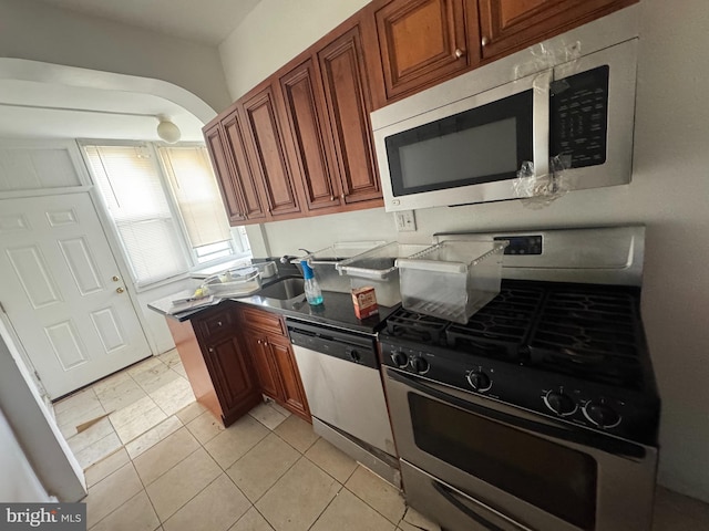 236 Randolph Pl NE, Washington, DC 20002 - kitchen with appliances with stainless steel finishes, arched walkways, brown cabinetry, and light tile patterned floors