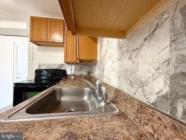 1343 Muhlenberg St, Reading, PA 19602 - kitchen view of black electric range, a sink, and brown cabinetry