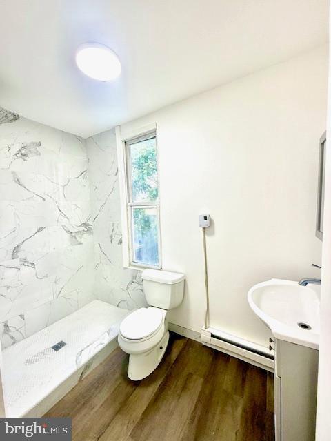 1343 Muhlenberg St, Reading, PA 19602 - full bath featuring a baseboard heating unit, vanity, a shower stall, toilet, and wood finished floors