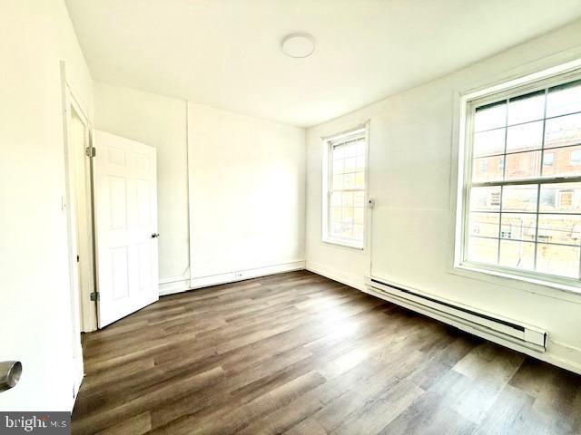 1343 Muhlenberg St, Reading, PA 19602 - unfurnished room featuring wood finished floors, a baseboard heating unit, plenty of natural light, and baseboards