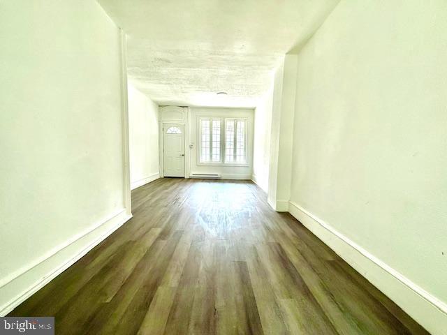1343 Muhlenberg St, Reading, PA 19602 - unfurnished living room featuring wood finished floors, baseboards, and a baseboard radiator