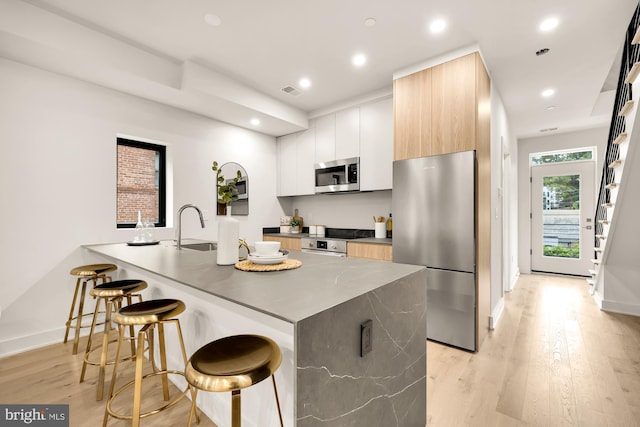 2647 41st St NW Unit 3, Washington, DC 20007 - kitchen with appliances with stainless steel finishes, modern cabinets, a kitchen breakfast bar, light wood-type flooring, and baseboards