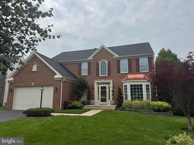 17 Sheridan Ln, Brunswick, MD 21758 - colonial inspired home with a garage, asphalt driveway, brick siding, a front lawn, and a shingled roof