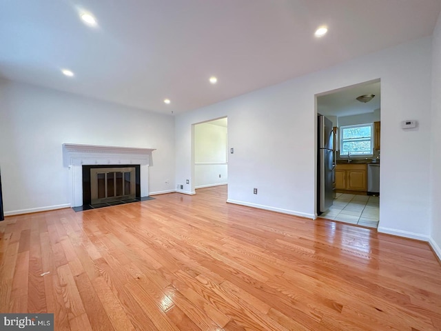 8432 Ravenswood Rd, New Carrollton, MD 20784 - unfurnished living room with light wood-style floors, baseboards, recessed lighting, and a fireplace with flush hearth