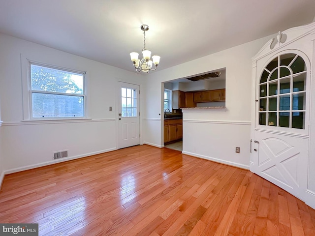 8432 Ravenswood Rd, New Carrollton, MD 20784 - unfurnished dining area featuring a chandelier, a sink, light wood finished floors, and baseboards