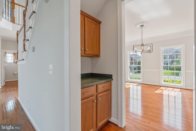 6513 Debhill Ln, Gainesville, VA 20155 - bar with light wood-style flooring, a chandelier, baseboards, stairway, and decorative light fixtures