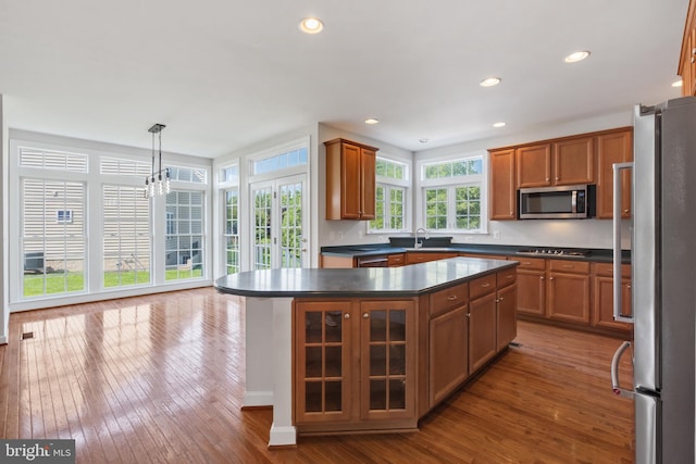 6513 Debhill Ln, Gainesville, VA 20155 - kitchen featuring appliances with stainless steel finishes, dark countertops, a sink, hardwood / wood-style floors, and brown cabinetry