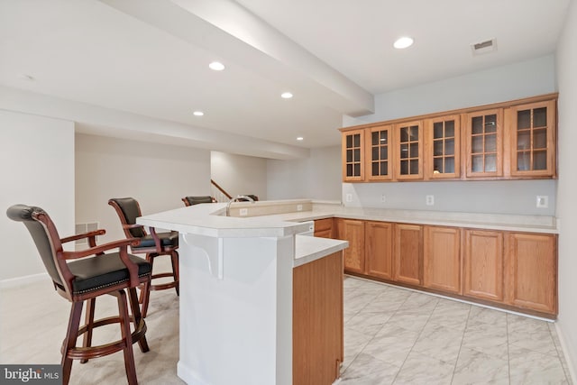 6513 Debhill Ln, Gainesville, VA 20155 - kitchen featuring a peninsula, recessed lighting, a breakfast bar area, light countertops, and glass insert cabinets
