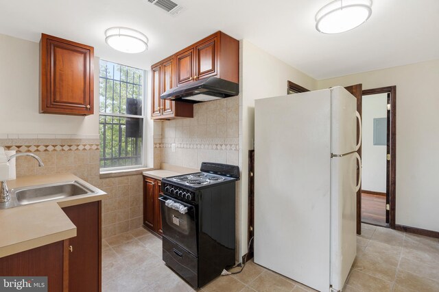2400 Druid Hill Ave, Baltimore, MD 21217 - kitchen featuring freestanding refrigerator, black range, under cabinet range hood, light countertops, and light tile patterned floors
