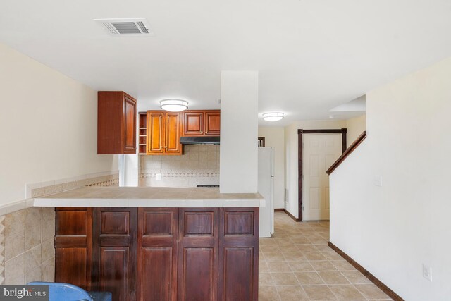 2400 Druid Hill Ave, Baltimore, MD 21217 - kitchen featuring under cabinet range hood, a peninsula, open shelves, backsplash, and brown cabinets