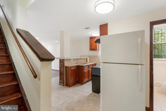 2400 Druid Hill Ave, Baltimore, MD 21217 - kitchen with freestanding refrigerator, stove, brown cabinetry, and under cabinet range hood