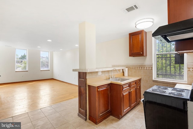 2400 Druid Hill Ave, Baltimore, MD 21217 - kitchen featuring black electric range, exhaust hood, light countertops, light tile patterned flooring, and brown cabinetry