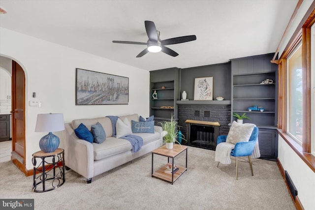 3330 E Prospect Rd, York, PA 17402 - carpeted living area featuring arched walkways, a ceiling fan, a brick fireplace, baseboards, and built in shelves