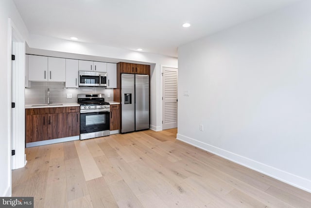 845 19th St NE Unit 4, Washington, DC 20002 - kitchen featuring appliances with stainless steel finishes, a sink, light wood-style flooring, light countertops, and decorative backsplash