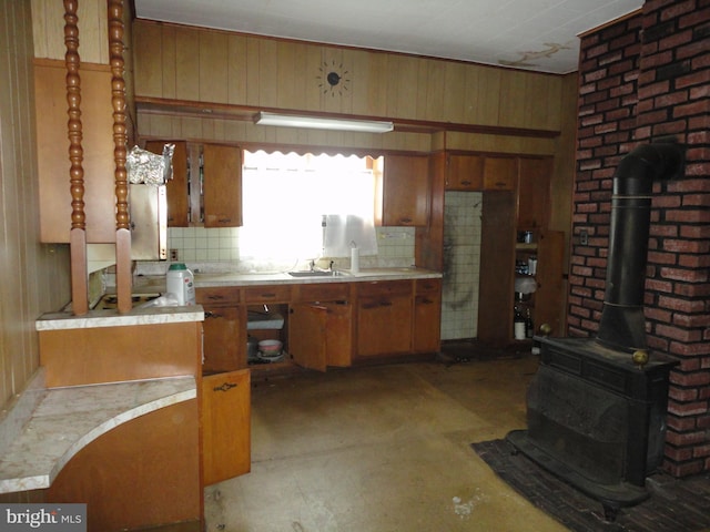 11 W Glendale Ave, Pleasantville, NJ 08232 - kitchen featuring a wood stove, light countertops, wooden walls, and brown cabinetry