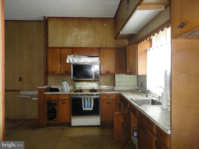 11 W Glendale Ave, Pleasantville, NJ 08232 - kitchen featuring white stove, a sink, brown cabinetry, backsplash, and wooden walls