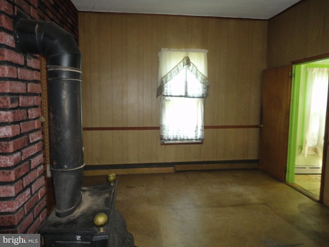 11 W Glendale Ave, Pleasantville, NJ 08232 - unfurnished living room featuring wooden walls, a wood stove, a baseboard radiator, and concrete flooring