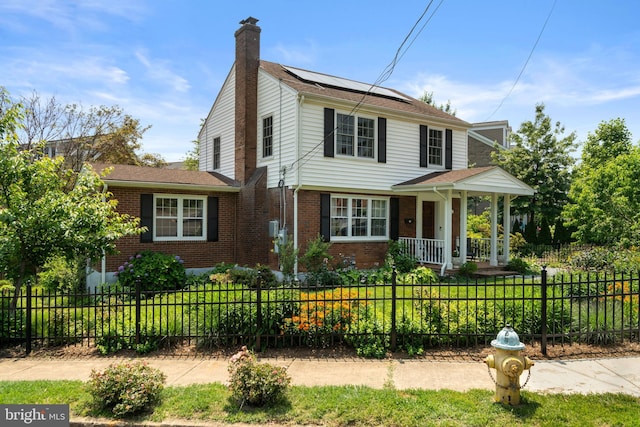 5600 11th St N, Arlington, VA 22205 - view of front of home featuring brick siding, roof mounted solar panels, a chimney, and covered porch