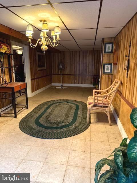 7316 Pittville Ave, Philadelphia, PA 19126 - living area featuring wooden walls, a chandelier, a paneled ceiling, and baseboards
