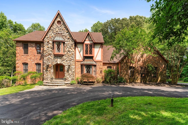 15713 Holly Grove Rd, Silver Spring, MD 20905 - tudor-style house with a shingled roof, a front lawn, stone siding, and brick siding