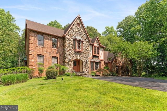 15713 Holly Grove Rd, Silver Spring, MD 20905 - tudor house with a front lawn, roof with shingles, and stone siding