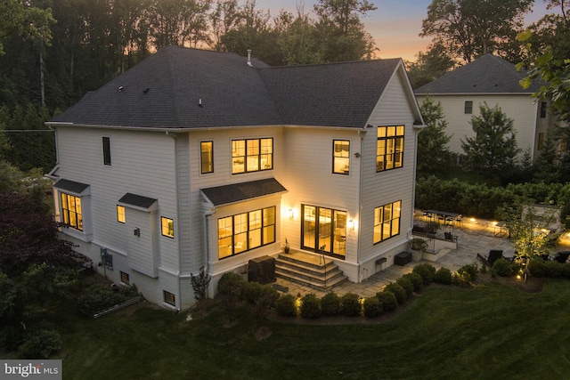 717 Miller Ave, Great Falls, VA 22066 - back of house at dusk with a patio area, a yard, and roof with shingles