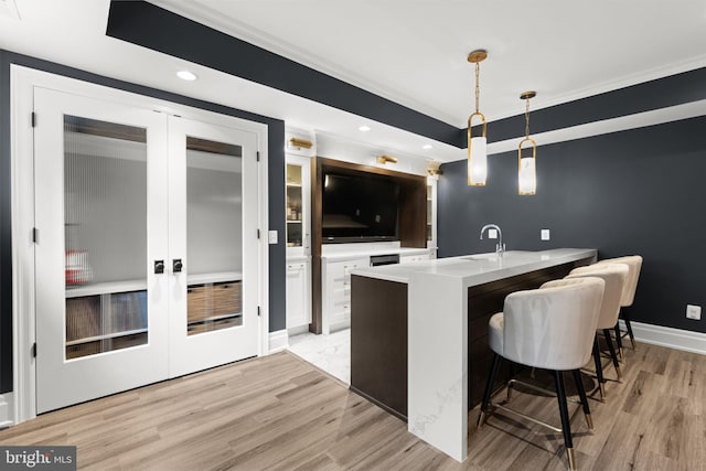 717 Miller Ave, Great Falls, VA 22066 - kitchen featuring french doors, light wood-style flooring, light countertops, a kitchen breakfast bar, and pendant lighting