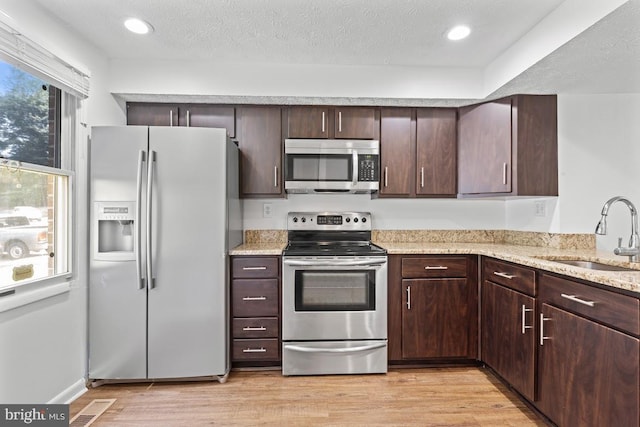13825 Palmer House Way Unit 32-237, Silver Spring, MD 20904 - kitchen with appliances with stainless steel finishes, dark brown cabinetry, light stone countertops, light wood finished floors, and recessed lighting