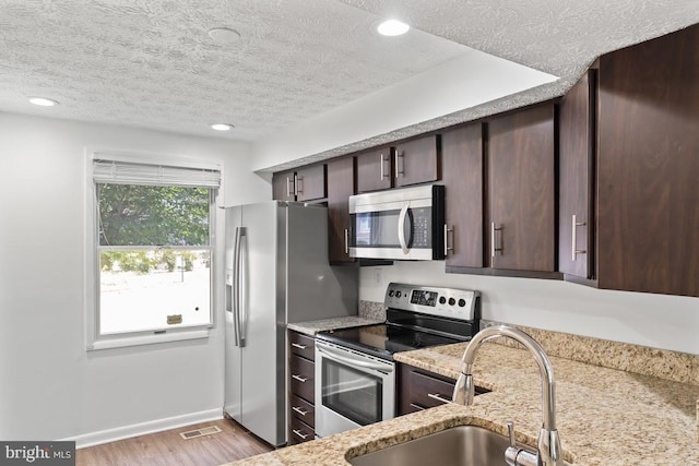13825 Palmer House Way Unit 32-237, Silver Spring, MD 20904 - kitchen with stainless steel appliances, dark brown cabinets, a textured ceiling, light wood finished floors, and light stone countertops