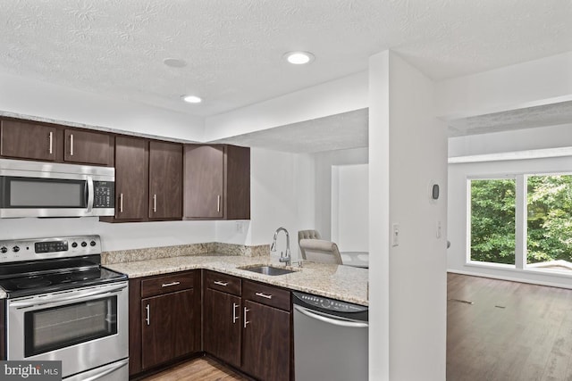 13825 Palmer House Way Unit 32-237, Silver Spring, MD 20904 - kitchen featuring appliances with stainless steel finishes, light wood-type flooring, dark brown cabinetry, a textured ceiling, and light stone counters