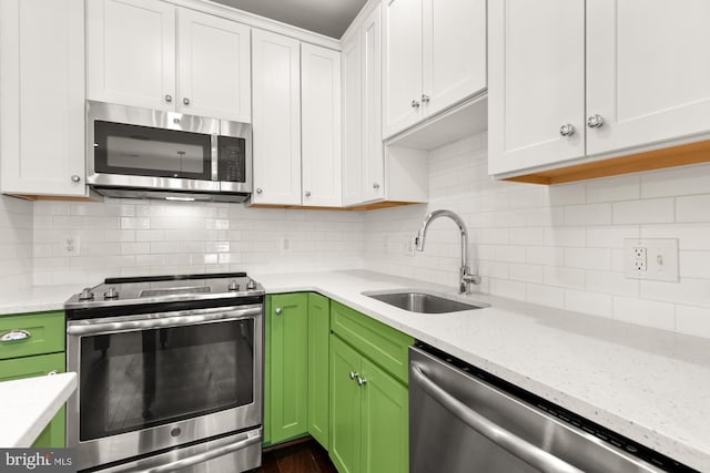 7229 Georgia Ave NW Unit A, Washington, DC 20012 - kitchen featuring stainless steel appliances, a sink, white cabinets, backsplash, and light stone counters