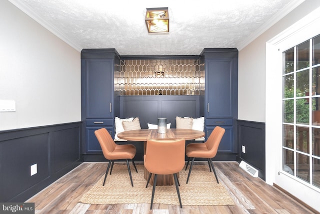 8755 Cather Ave, Manassas, VA 20110 - dining room with a decorative wall, wood finished floors, wainscoting, a textured ceiling, and crown molding