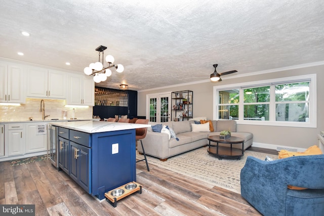 8755 Cather Ave, Manassas, VA 20110 - kitchen featuring open floor plan, a sink, white cabinets, a chandelier, and wood finished floors