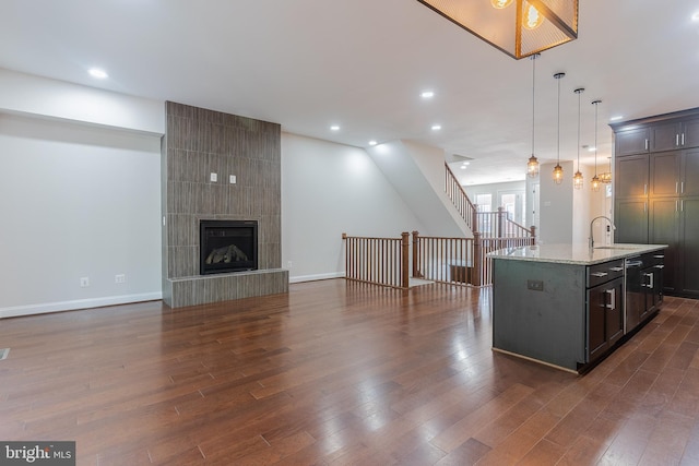 23480 Epperson Sq, Brambleton, VA 20148 - kitchen with dark wood-style floors, open floor plan, pendant lighting, light stone countertops, and a kitchen island with sink