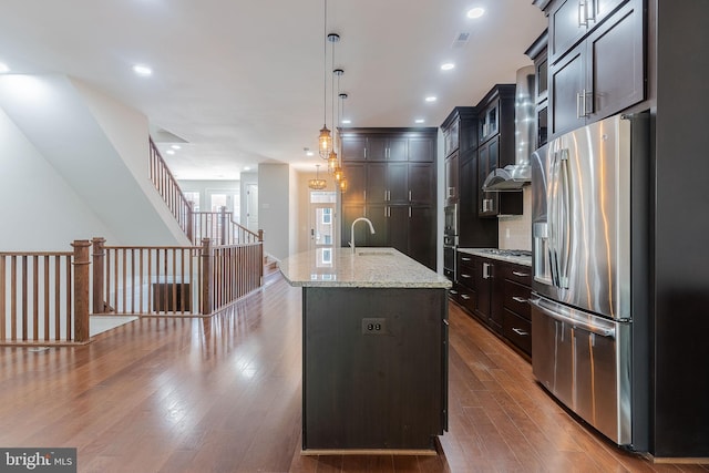 23480 Epperson Sq, Brambleton, VA 20148 - kitchen featuring stainless steel refrigerator with ice dispenser, dark wood-style flooring, hanging light fixtures, a center island with sink, and light stone counters